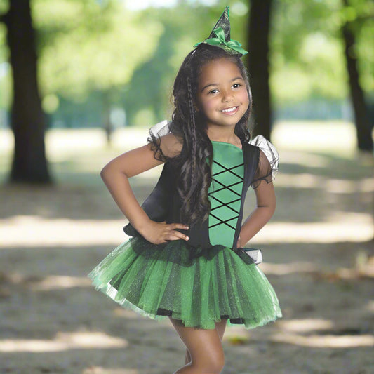 Child wearing a green and black witch costume on a white background